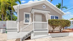 A single-story house with a front porch, a small staircase, and a fenced yard. - Poolside Paradise by Brightwild Heated Pool (Key West)