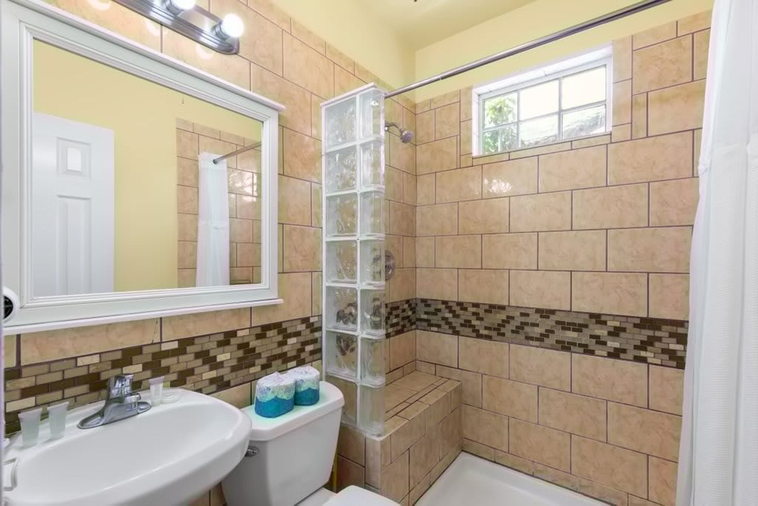 Un baño con ducha, inodoro, lavamanos y ventana.