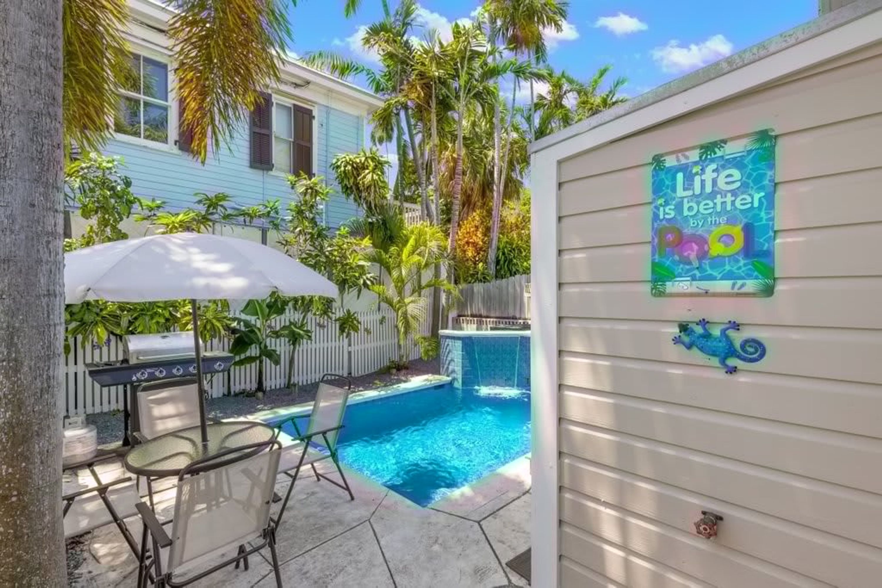 Un jardin avec une piscine, un barbecue et une terrasse avec des chaises.
