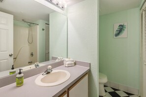 Un baño con un lavamanos blanco, un espejo grande y una ducha.