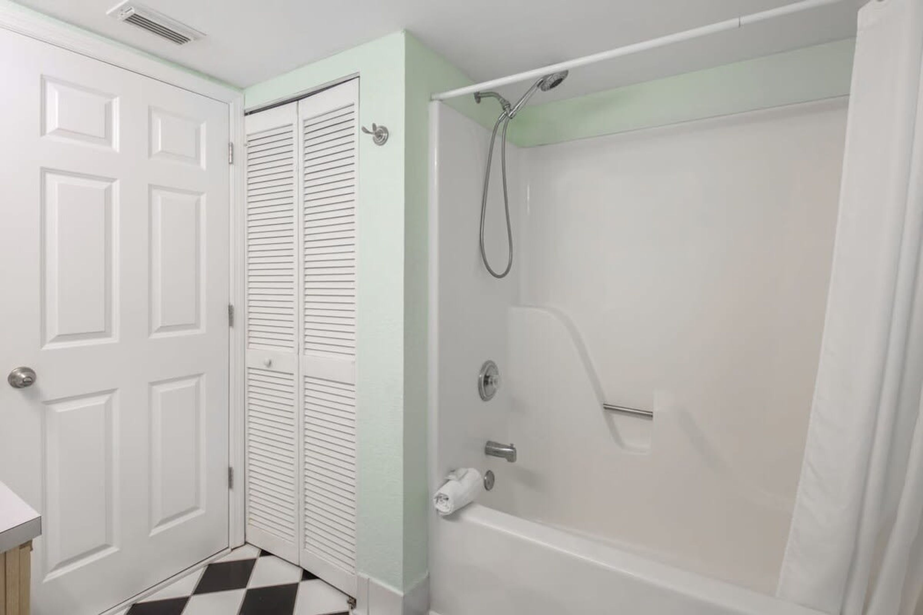 Une salle de bain avec une porte blanche, une baignoire blanche et une douche.