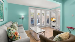 Una sala de estar con un sofá, un sillón y un mueble bajo para televisión con un televisor de pantalla plana.