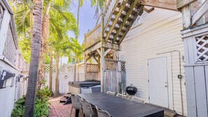 A patio with a table and chairs, a grill, and a wooden deck.