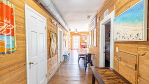 A wooden hallway with a bench, a door, and a painting on the wall.