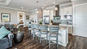 Une cuisine moderne avec des meubles blancs, un îlot central et des luminaires suspendus.