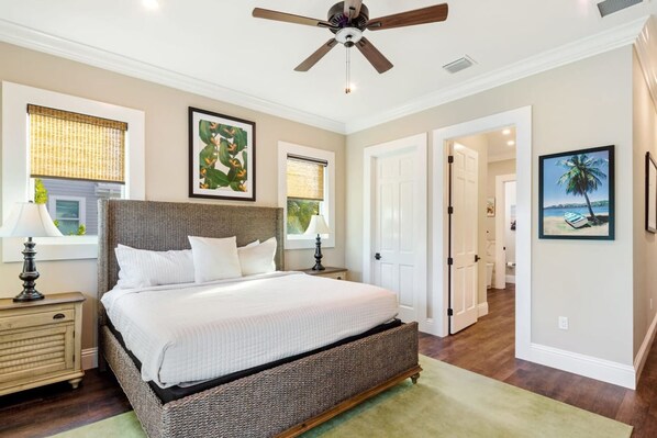 A bedroom with a large bed, a ceiling fan, and artwork on the walls. - Capmar House by Brightwild Huge Home Pool (Key West)