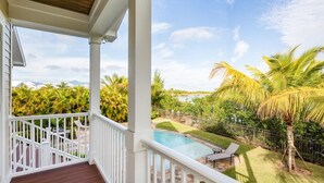 A balcony with a view of a swimming pool, palm trees, and a fenced yard. - Capmar House by Brightwild Huge Home Pool (Key West)
