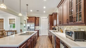 A spacious kitchen with wooden cabinets, a large island, and modern appliances. - Capmar House by Brightwild Huge Home Pool (Key West)