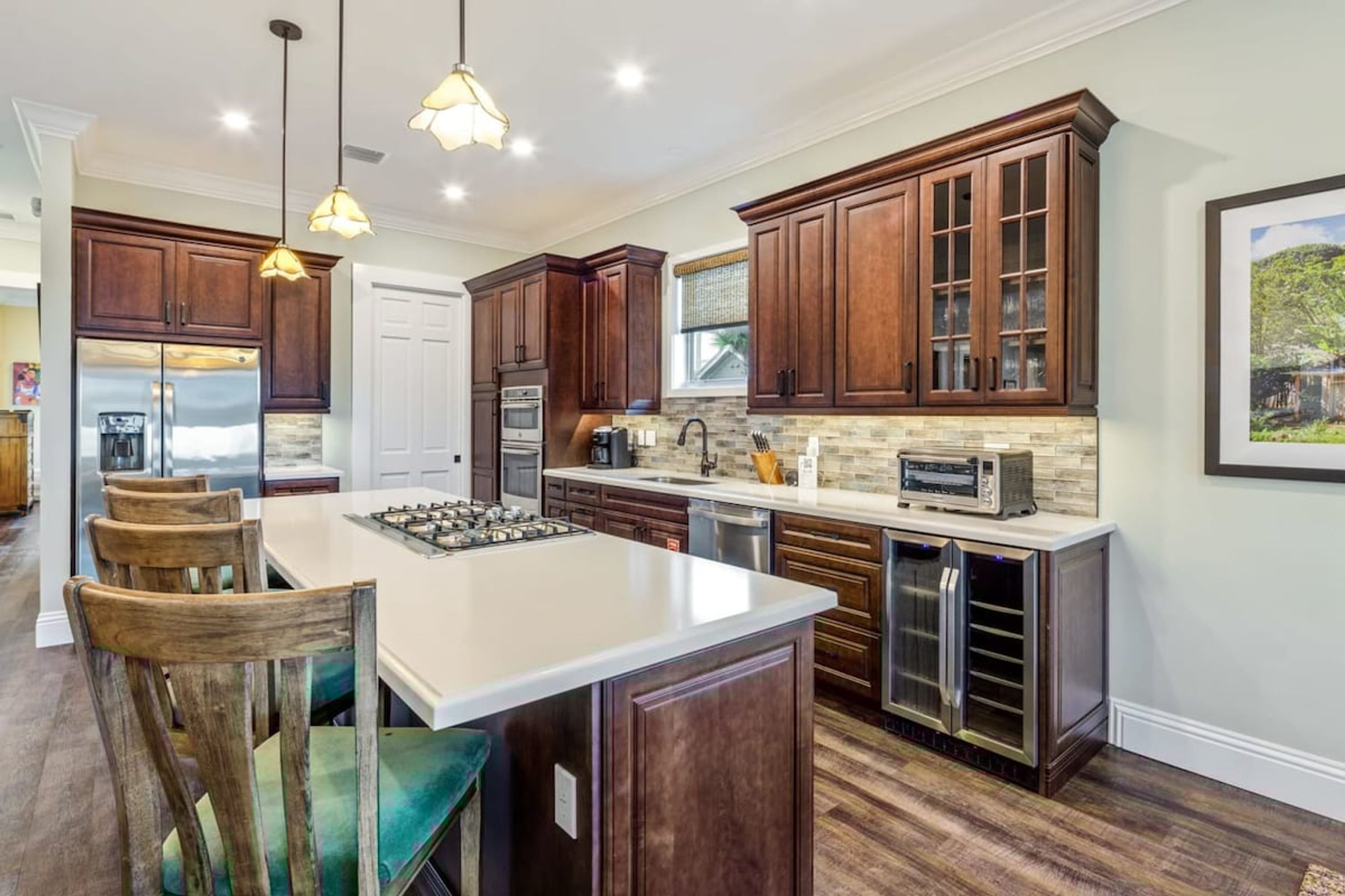 A modern kitchen with dark wood cabinets, a central island, stainless steel appliances, and pendant lighting.