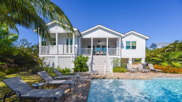 A white two-story house with a balcony and a swimming pool. - Capmar House by Brightwild Huge Home Pool (Key West)