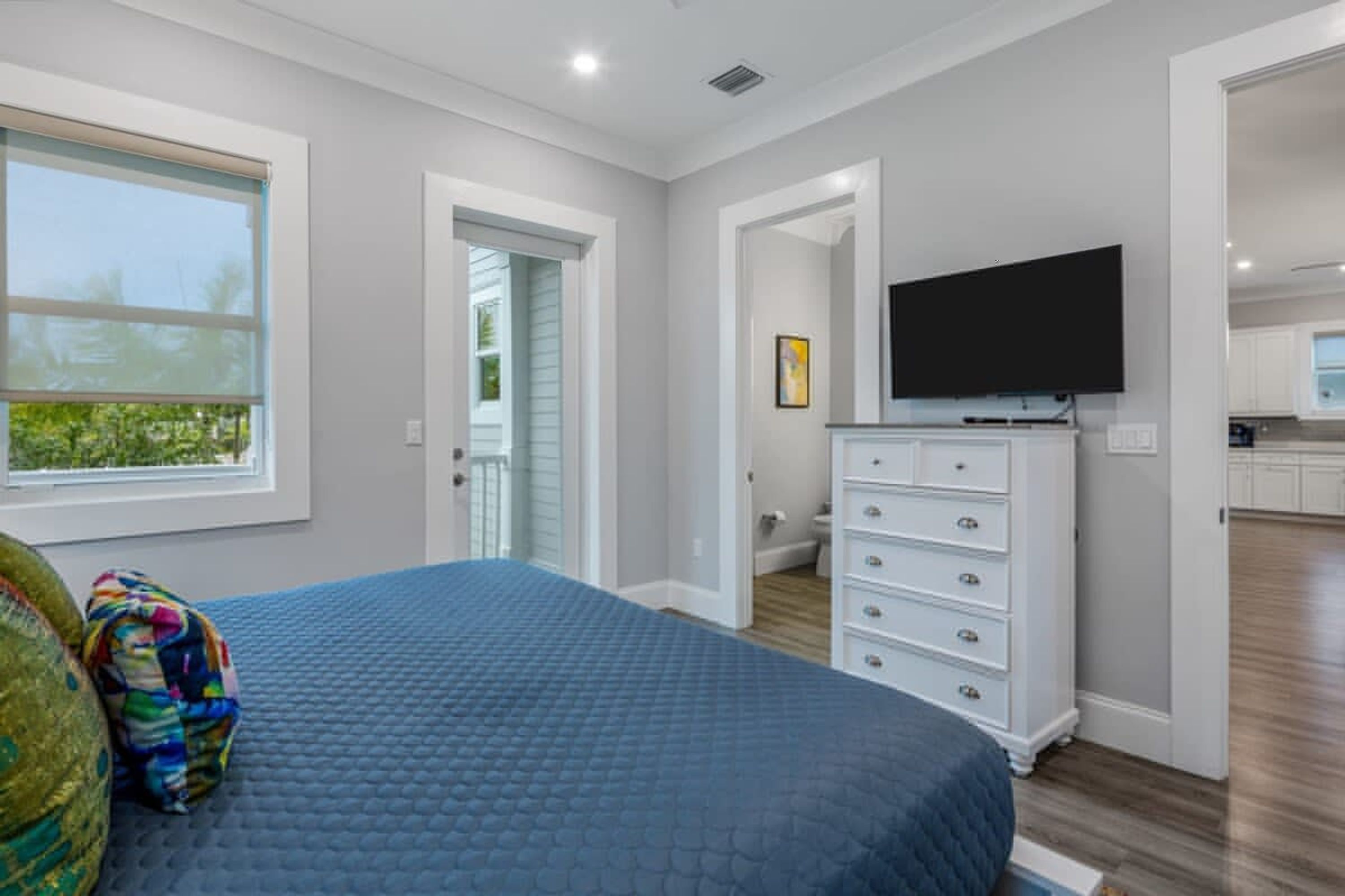 A bedroom with a bed, a dresser, a television, and a window.