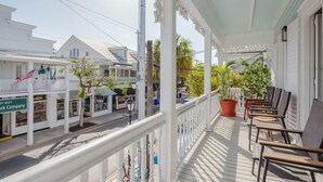 Een wit terras met een balustrade, plantenpotten en buitenmeubels.