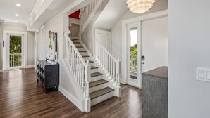 A spacious interior with a wooden staircase, a modern light fixture, and a view of the outdoors. - Spindrift House by Brightwild Huge Pool Dock (Key West)