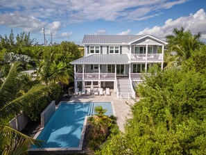 A two-story house with a swimming pool, surrounded by lush greenery and palm trees. - Spindrift House by Brightwild Huge Pool Dock (Key West)