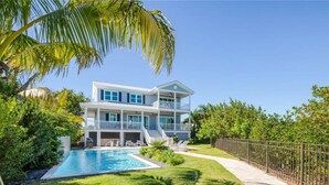 A two-story house with a swimming pool, surrounded by lush greenery and a fenced yard. - Spindrift House by Brightwild Huge Pool Dock (Key West)