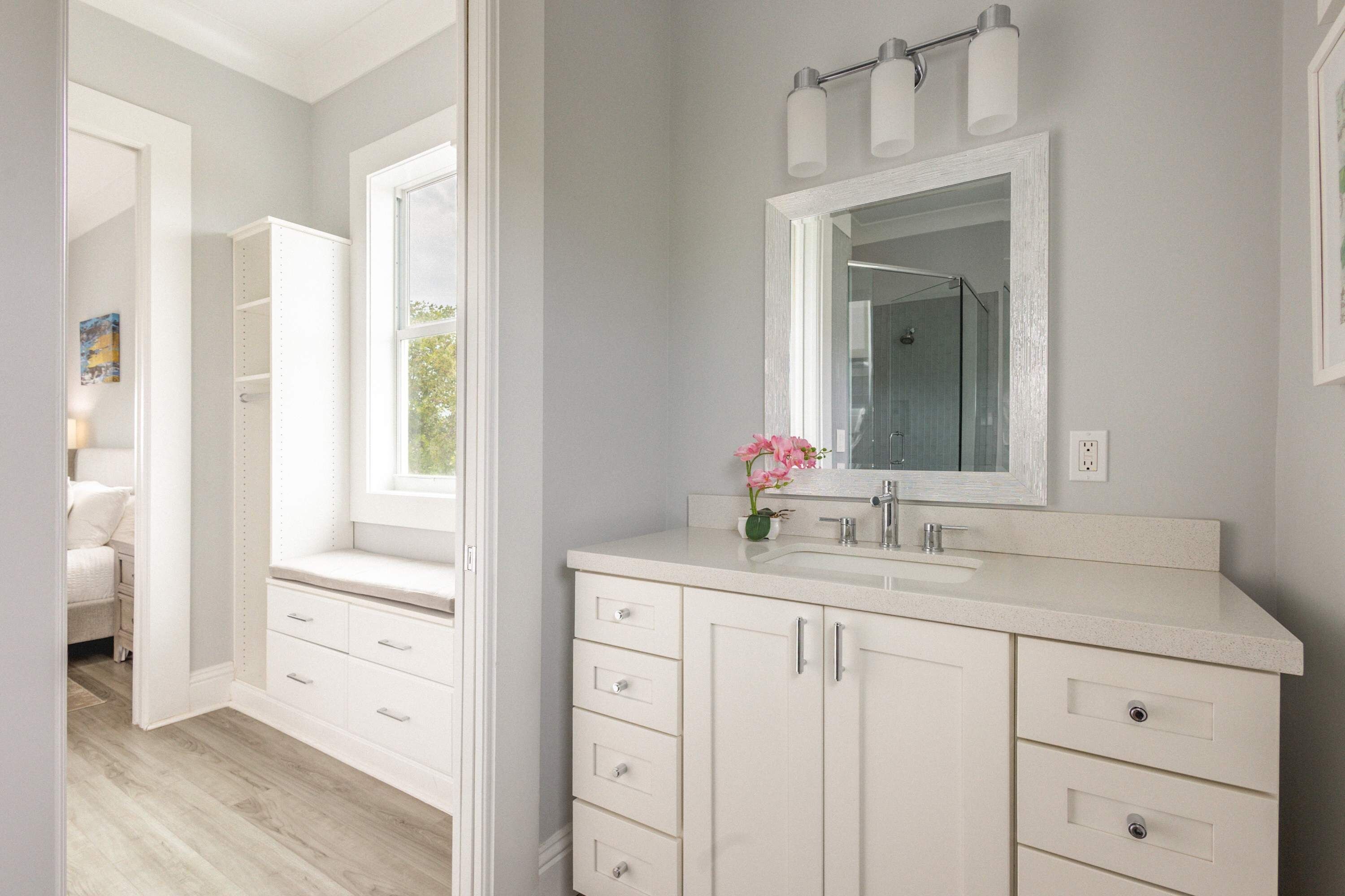 Une salle de bain moderne avec un grand miroir, une douche et un meuble-lavabo doté de tiroirs.