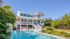 A two-story house with a swimming pool, outdoor seating, and a fenced yard. - Spindrift House by Brightwild Huge Pool Dock (Key West)