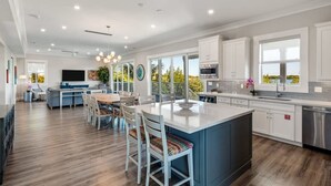 A spacious kitchen with a large island, white cabinetry, and a view of the outdoors. - Spindrift House by Brightwild Huge Pool Dock (Key West)
