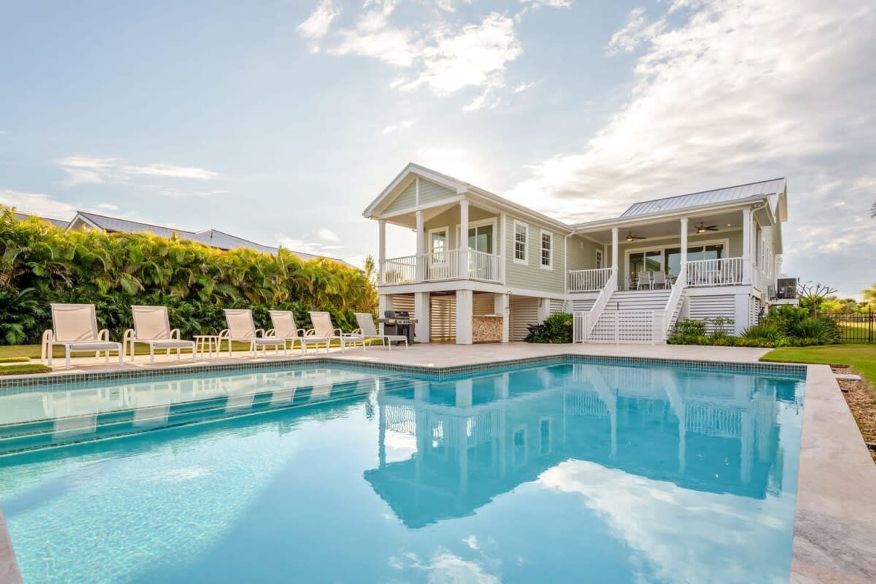 A large house with a swimming pool, a covered patio, and a staircase leading to a second floor.