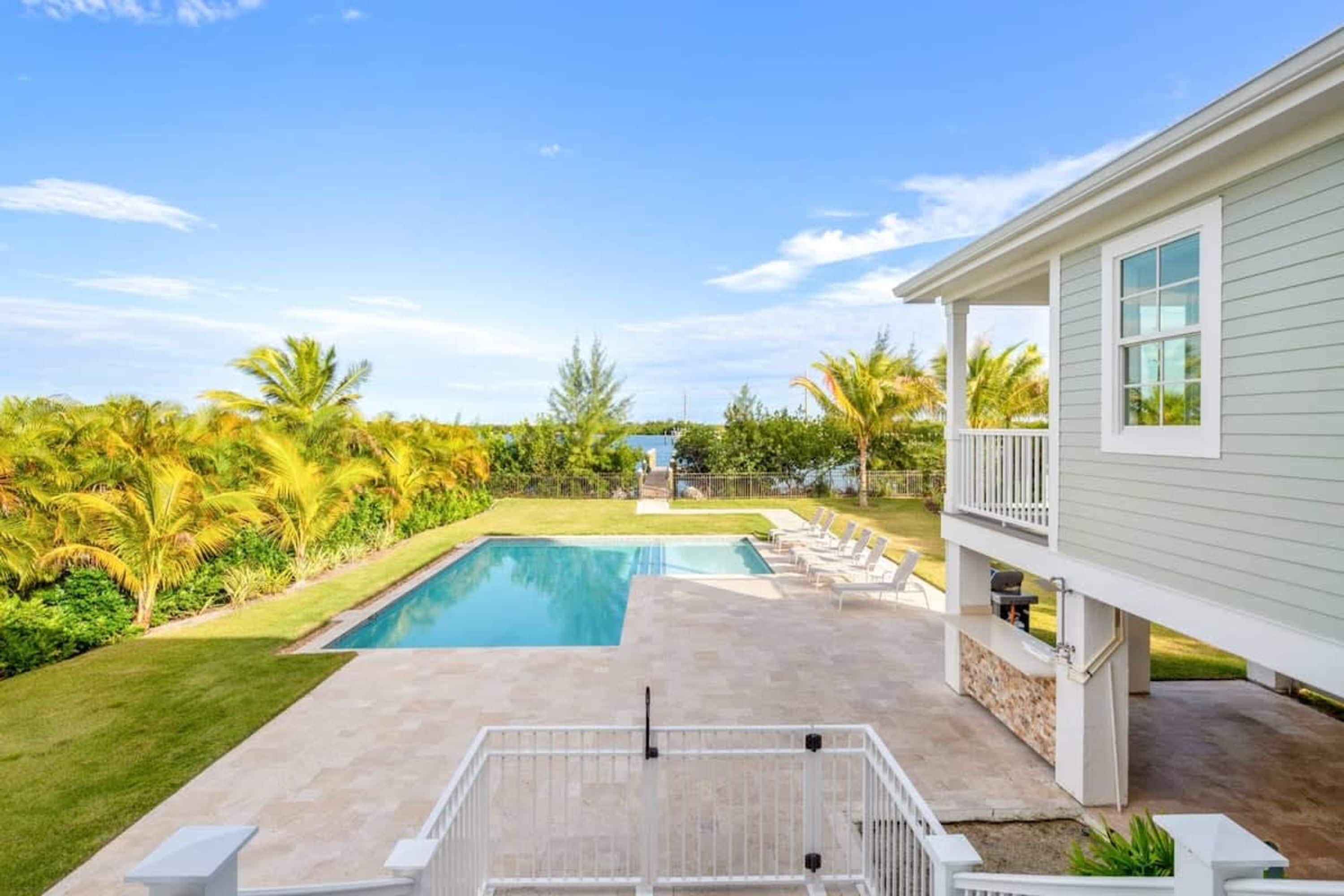 A backyard with a swimming pool, a covered patio, and a house.