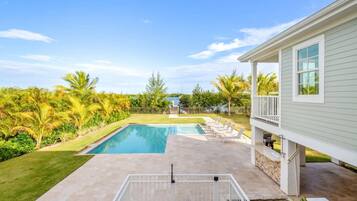 A backyard with a swimming pool, a covered patio, and a house.