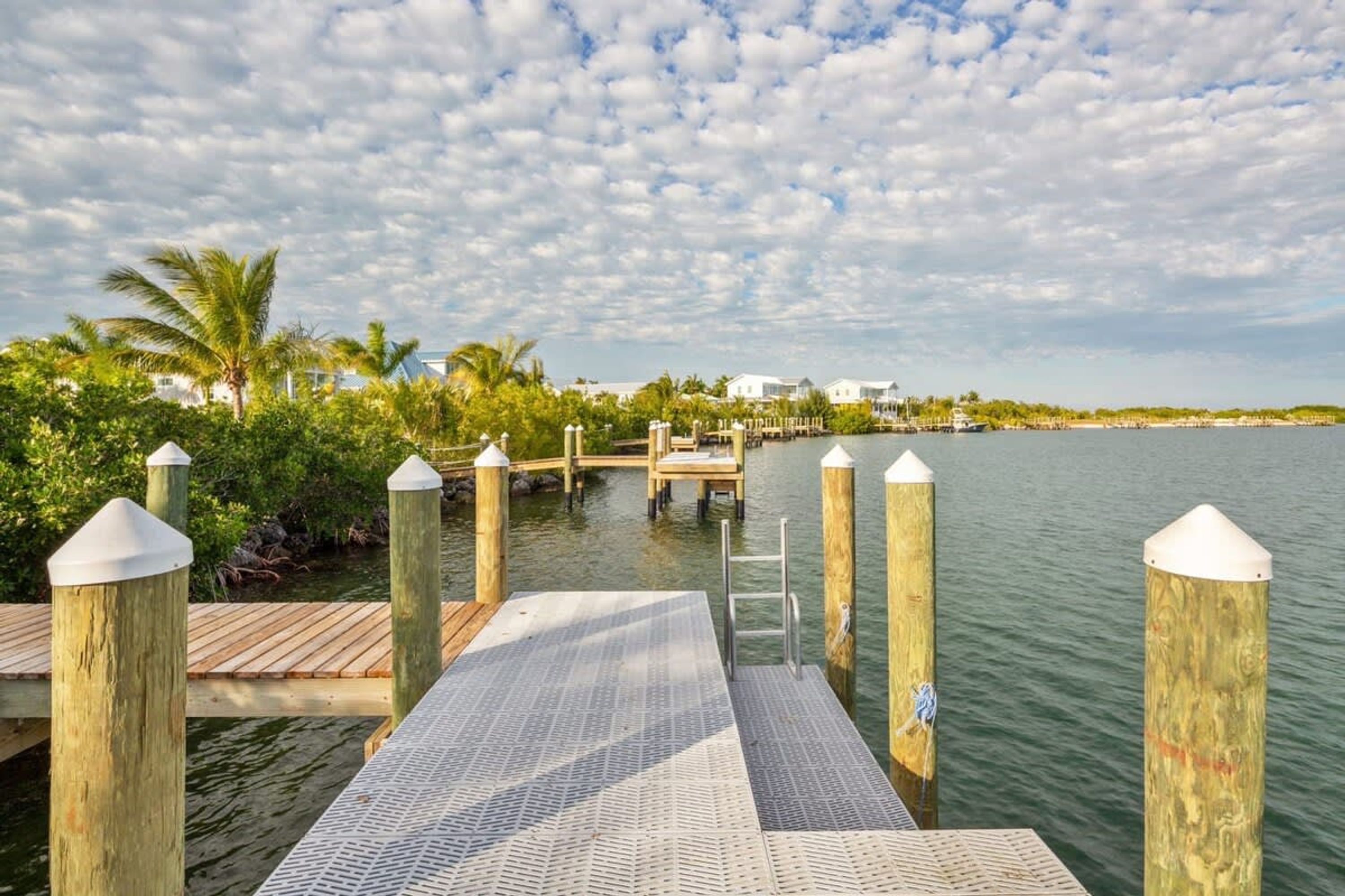 A wooden dock leading into calm waters with a clear sky.