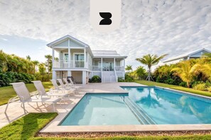 A two-story house with a pool, surrounded by palm trees and a clear sky. - Mirador House by Brightwild Pool Dock (Key West)