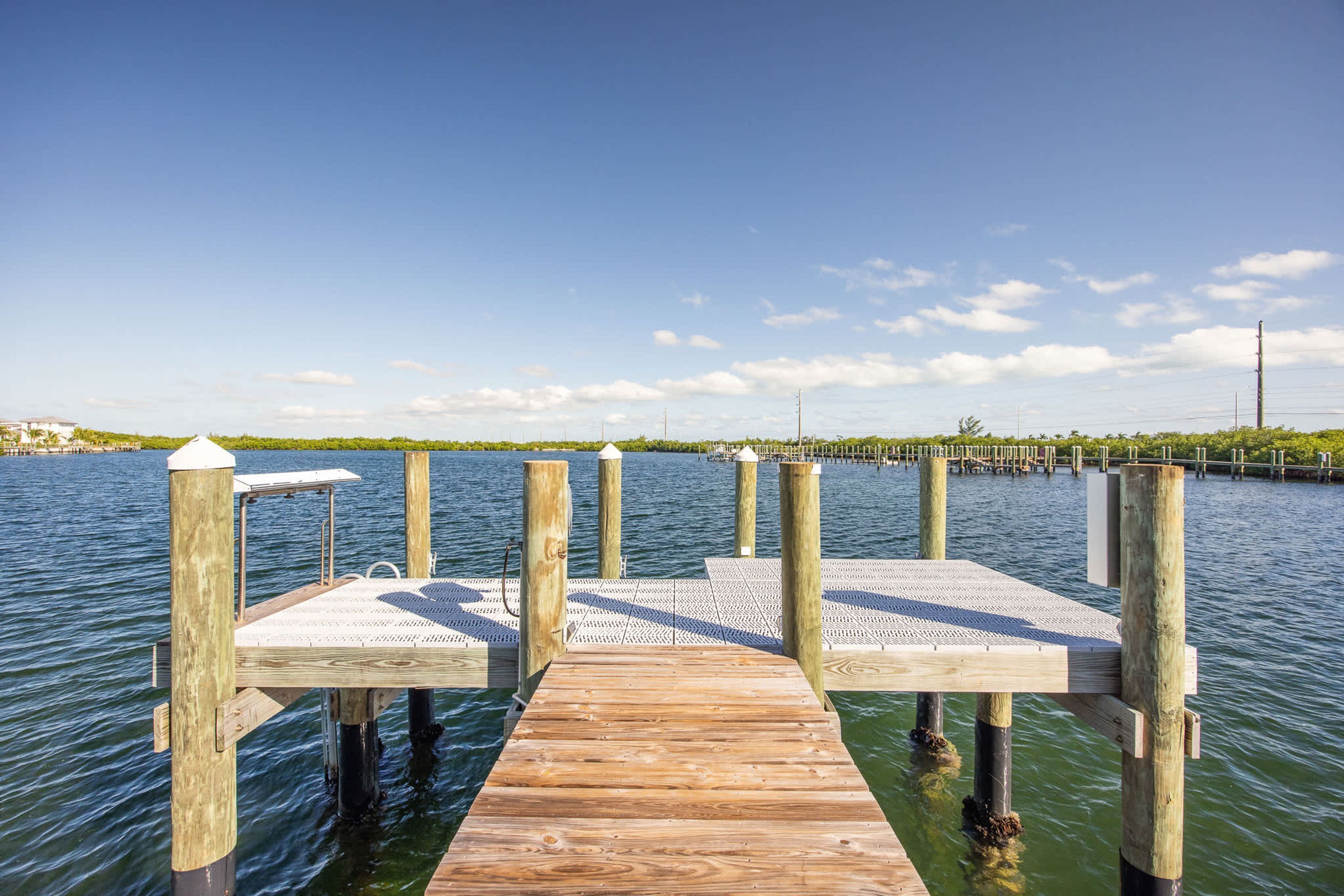 A wooden pier extending into calm water, with a clear sky above.