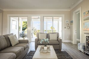 A living room with two sofas, a coffee table, and a view of the outdoors. - Waterlane House by Brightwild Pool Boat Dock (Key West)
