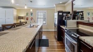A modern kitchen with a central island, built-in appliances, and pendant lighting. - Cloud Suite on Duval Luxury Condo Epic Location (Key West)