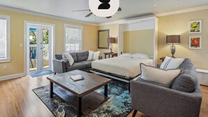A modern bedroom with a bed, two gray sofas, a coffee table, and a ceiling fan. - Cloud Suite on Duval Luxury Condo Epic Location (Key West)