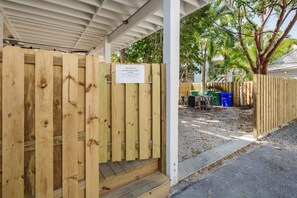 A wooden gate with a sign indicating 'Sky Suites' and a covered outdoor area with a concrete path and trees. - Cloud Suite on Duval Luxury Condo Epic Location (Key West)