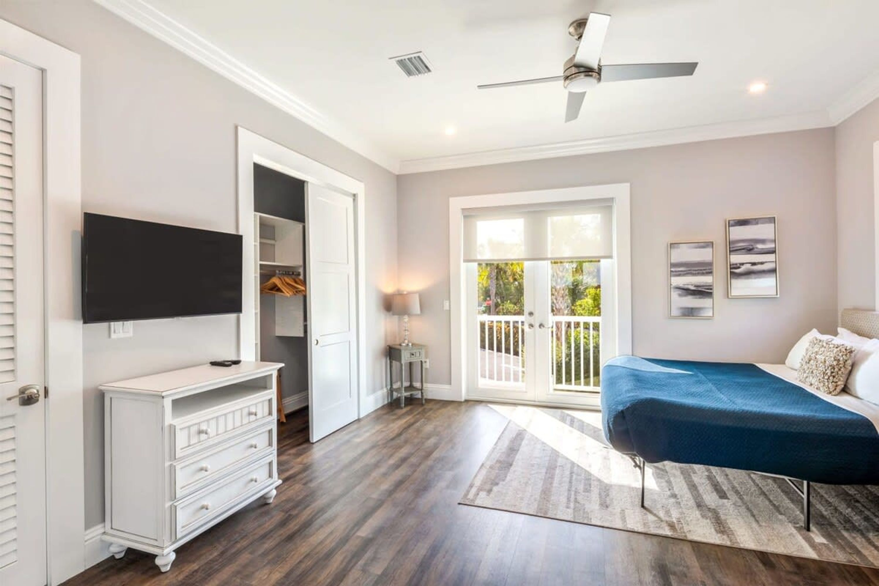 A bedroom with a bed, a TV, a wardrobe, and a balcony with a view.
