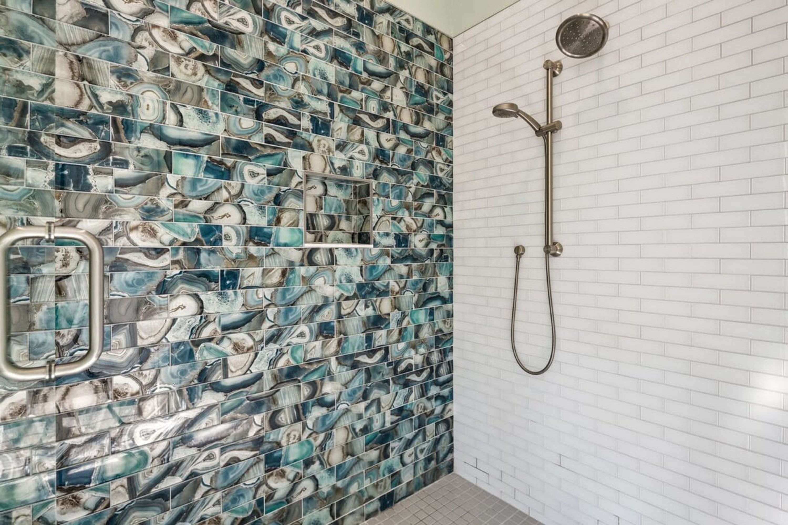 Un baño con pared de diseño de mármol y zona de ducha con azulejos blancos.