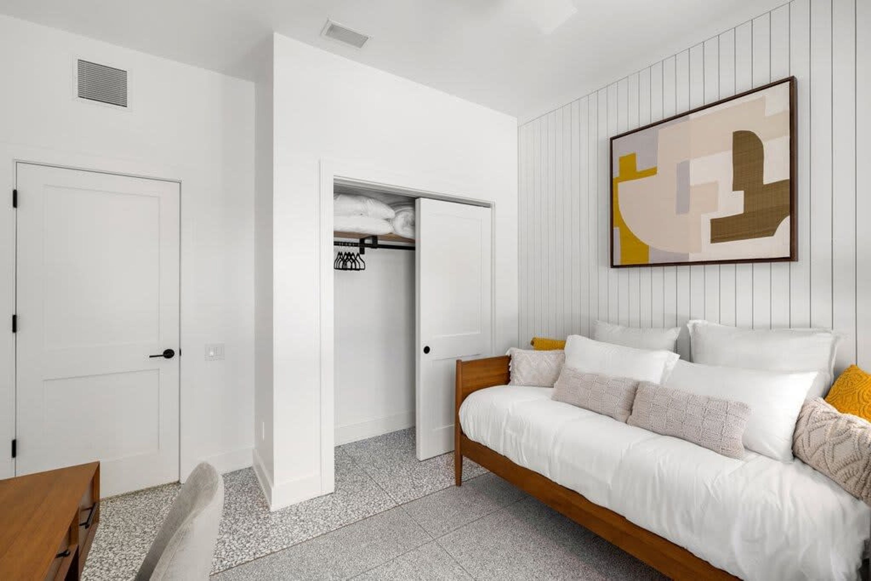 Ein modernes Schlafzimmer mit Bett, Kleiderschrank und einem Bild an der Wand.