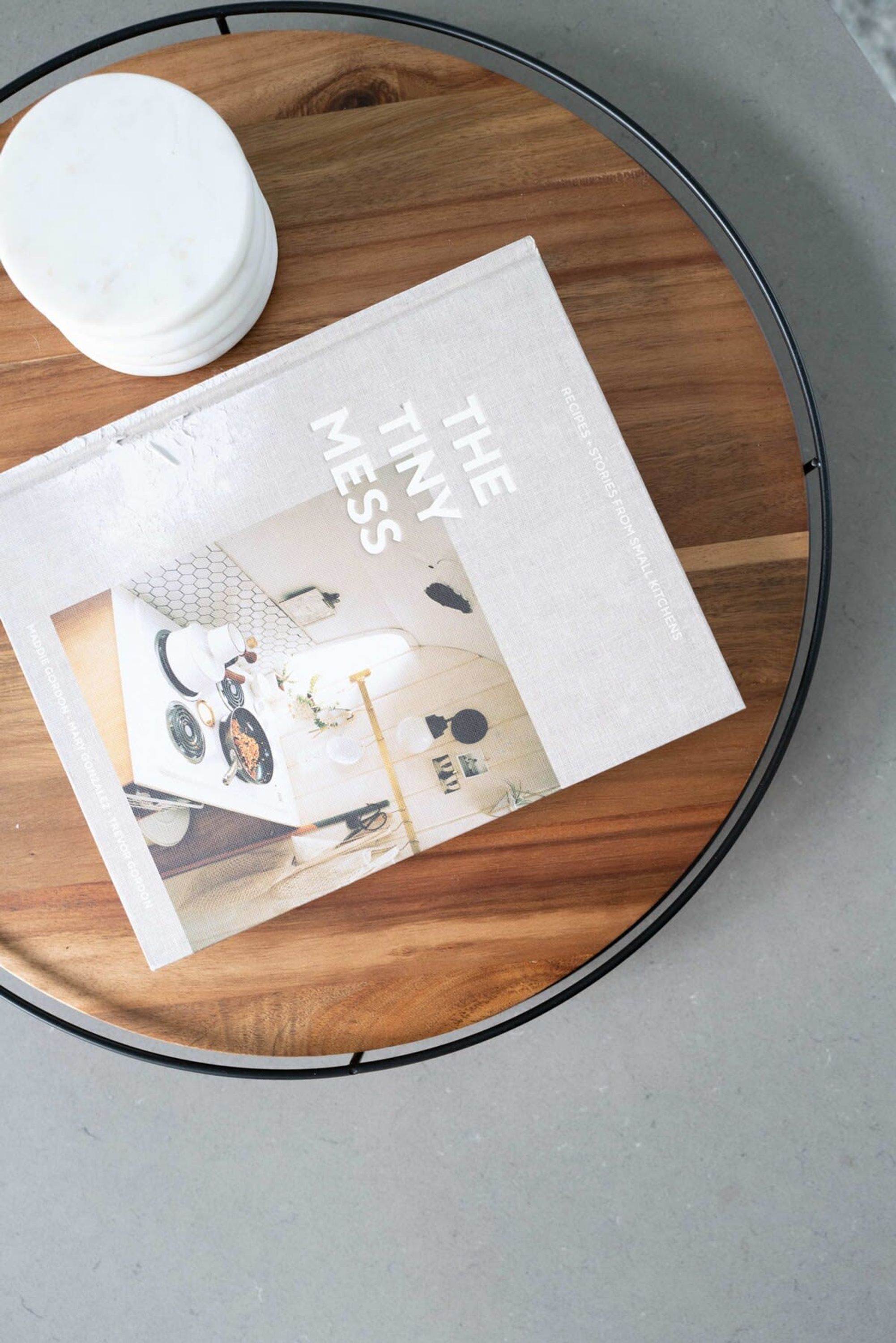 A magazine titled "The Tiny Mess" on a round wooden table.