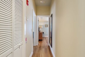 A narrow hallway with wooden flooring, white walls, and a door with horizontal slats. - Sky Suites Retreat by Brightwild 2 Stunning Condos (Key West)