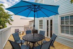 A deck with a round table and chairs, a blue umbrella, and a white railing. - Sky Suites Retreat by Brightwild 2 Stunning Condos (Key West)