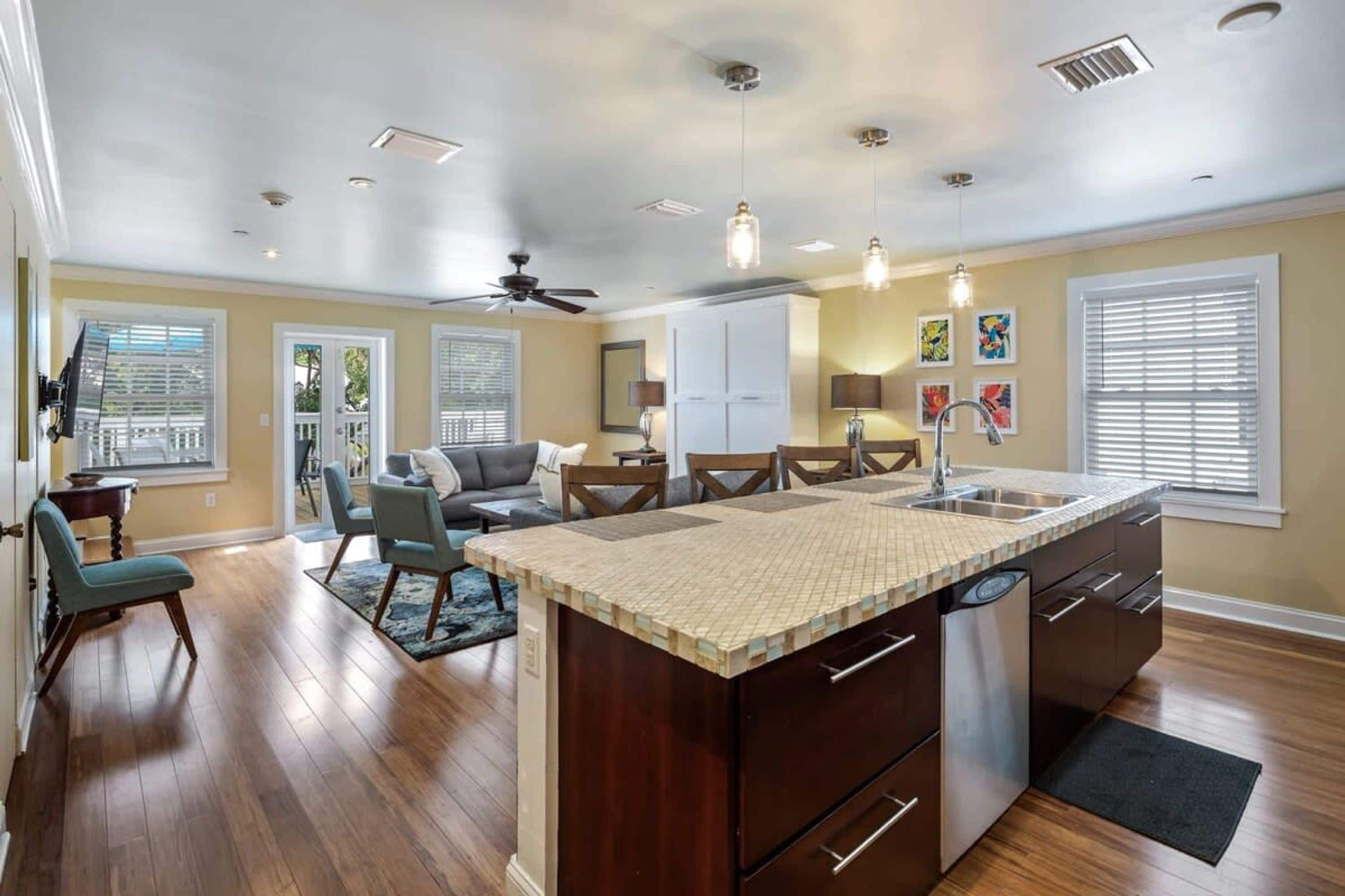 A spacious kitchen with a central island, wooden flooring, and pendant lighting.