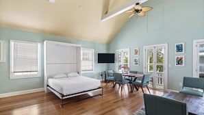 Une chambre à coucher avec un lit, un bureau, des chaises et un ventilateur de plafond.
