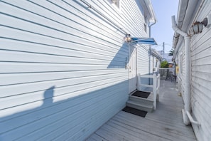 A narrow wooden deck with a blue awning, white siding, and a small porch area. - Sky Suites Retreat by Brightwild 2 Stunning Condos (Key West)