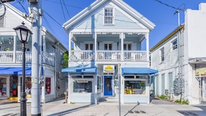 Un bâtiment à deux étages doté d’un balcon, d’un auvent bleu et d’une devanture avec une enseigne indiquant « Shave Ice ».