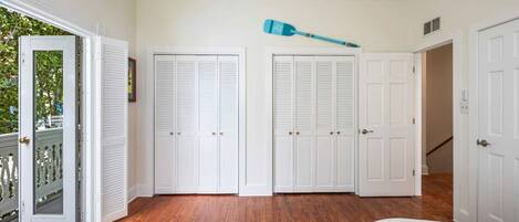 A room with wooden flooring, white doors, and a blue paddle broom on the ceiling.