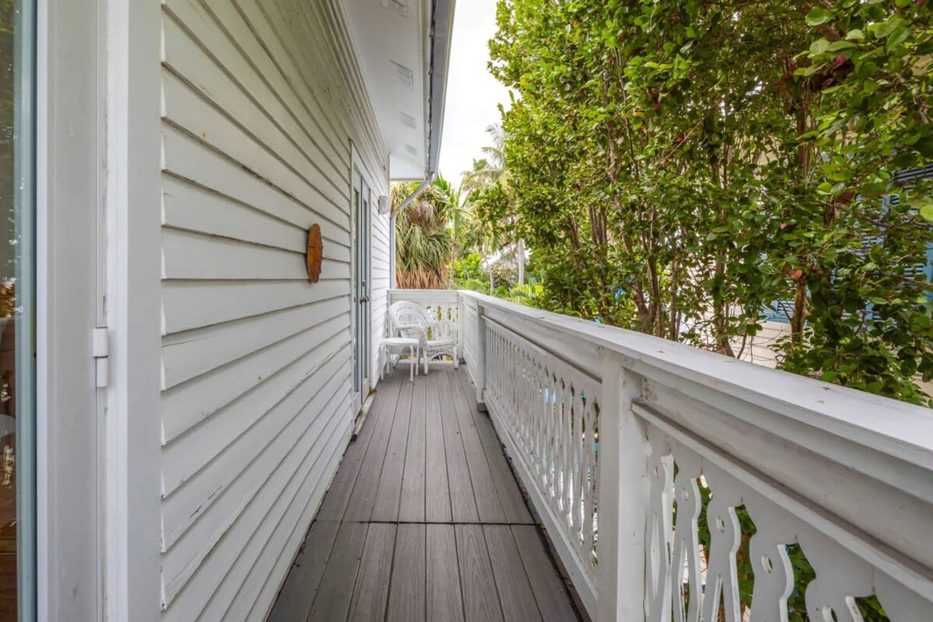 A covered porch with white railings and a wooden floor.