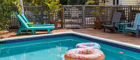 A swimming pool with inflatable rings, deck chairs, and umbrellas.