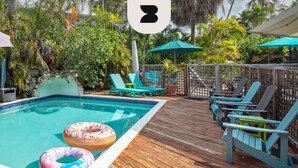 A wooden deck with a pool, lounge chairs, and umbrellas. - Sunnyside Up by Brightwild Pool Parking (Key West)