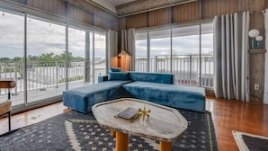 Un salon spacieux avec un grand canapé d’angle, une table basse et une vue sur la ville grâce à de grandes fenêtres.