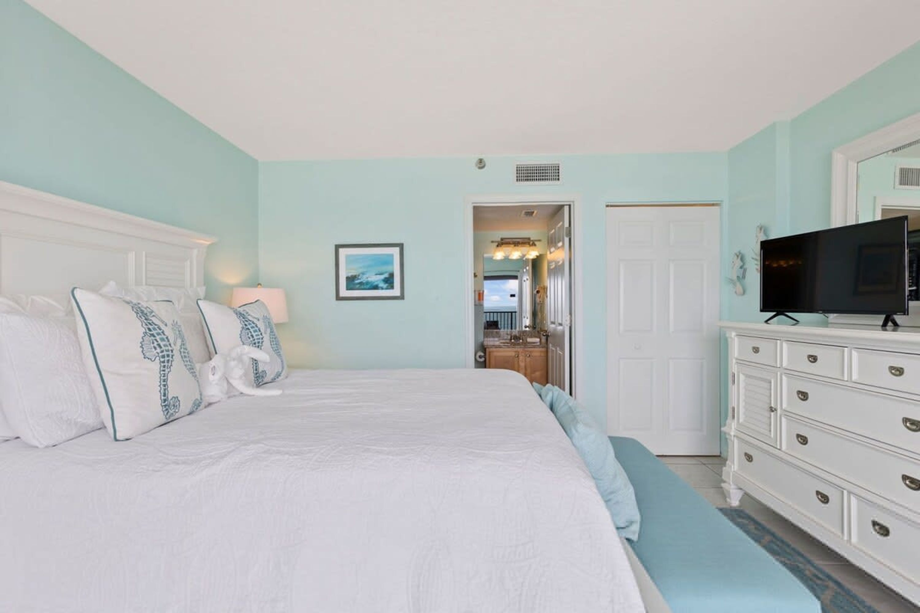 A bedroom with a large bed, a dresser, and a television.