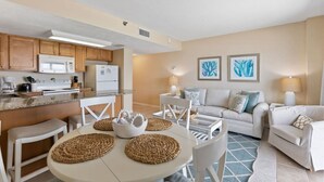 Una cocina moderna con armarios de madera, un refrigerador blanco y una zona de comedor con una mesa redonda y individuales tejidos.