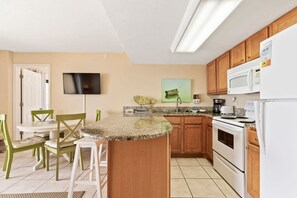 Una cucina compatta con zona pranzo, una TV a schermo piatto montata a parete, un forno a microonde e un frigorifero.